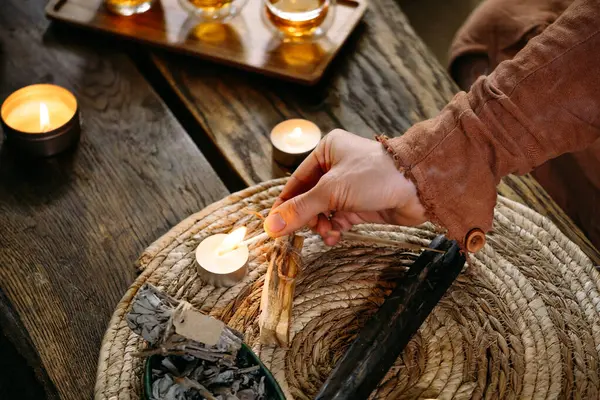 Lighting up candles on the table with matches. Women hand holding fire. Cozy evening home decoration.