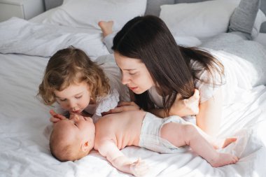 Büyük abla, anne ve küçük erkek kardeş iletişim kuruyor. Evde oynayan iki küçük, şirin beyaz çocuk kardeş. Sevimli gülümseyen aile birlikte yatıyor. Otantik samimi yaşam tarzı evcil anlar. 