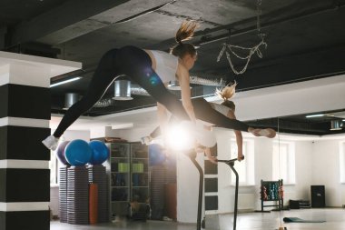 Spor salonunda atlama antrenmanı yapan bir grup kadın. Modern bir spor salonunda insanlar trambolinde zıplıyorlar, havada yükseliyorlar, zorlu bir egzersizle bacaklarını açıyorlar..