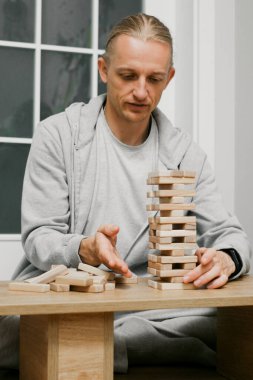 Kişi evdeki odasındaki ahşap kuledeki blokları dikkatlice istifliyor. Dijital detoks ve konsantrasyon. Kaliteli zaman çevrimdışı