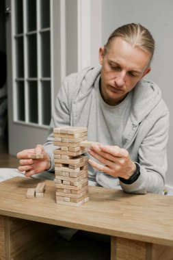Kişi evdeki odasındaki ahşap kuledeki blokları dikkatlice istifliyor. Dijital detoks ve konsantrasyon. Kaliteli zaman çevrimdışı