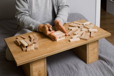 Kişi evdeki odasındaki ahşap kuledeki blokları dikkatlice istifliyor. Dijital detoks ve konsantrasyon. Kaliteli zaman çevrimdışı