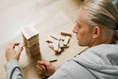 Erkek oyuncu tahta blokları dengeler, rekabetçi bir oyun ortamında kuleyi devirmemeye çalışır