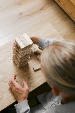 Erkek oyuncu tahta blokları dengeler, rekabetçi bir oyun ortamında kuleyi devirmemeye çalışır