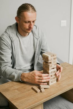 Erkek oyuncu tahta blokları dengeler, rekabetçi bir oyun ortamında kuleyi devirmemeye çalışır