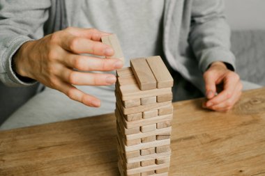 Kişi evdeki odasındaki ahşap kuledeki blokları dikkatlice istifliyor. Dijital detoks ve konsantrasyon. Kaliteli zaman çevrimdışı