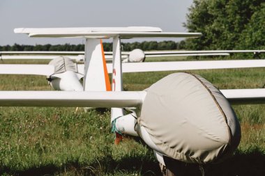 Glider fixed-wing motorless aircraft covered standing on airdrome parking lot, soaring club airfield clipart