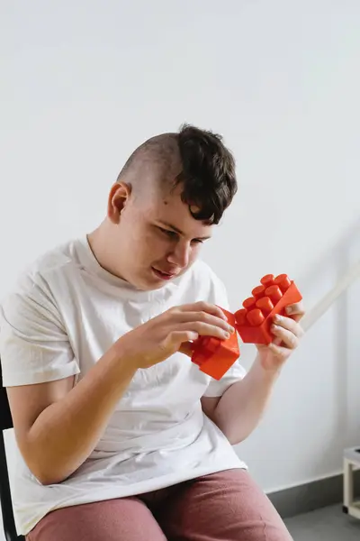 stock image Disabled teenage child build from blocks Boy with cerebral palsy doing activities for Children with Special Needs over white background. creativity, fine motor skills, rehabilitation, learning at home