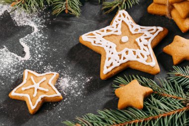 Noel arkaplanı, ev yapımı yıldız şeklinde zencefilli kurabiyelerle siyah masa üzerinde krema, kopyalama alanı. Kutlama yemekleri, kartpostal, kutlama gelenekleri. çam ağacı brunch