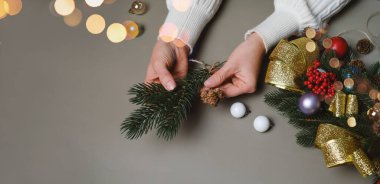 Noel çelengi yapan kadın, en iyi manzara. Çiçekçi eller şenlikli dekorasyon yaratıyor. Fotokopi alanı ve pankartı olan bir Noel çelengi atölyesi. Üst görünüm