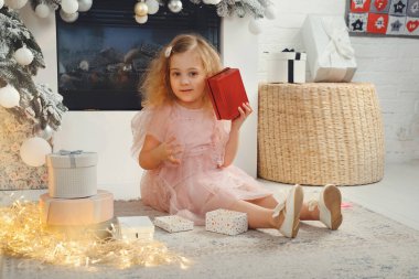 Kıvırcık kız Noel ağacının yanında hediyeler açar..