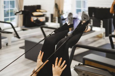 Stüdyodaki reformcular üzerinde pilates yaparken bacağını kaldıran kişi. Bacaklar spor salonunda yakın plan., 