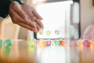 Kadın Oyuncu, masa üstü oyunu oturumuna hazırlanıyor. Kadın ellerinde zar. Masa oyunları konsepti. Uzayı kopyala Yeşil zarları kadınların elinde toplayın. Servet ve şansla dolu heyecan verici boş zaman.