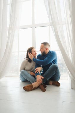 Çiftler güneşli pencerelerde yan yana oturur sevgi ve bağlılık dolu hassas anların tadını çıkarırlar. Evde ailece vakit geçirmenin sıcaklığı.