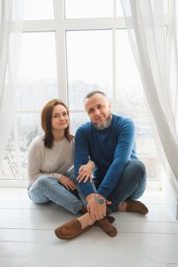 Çiftler güneşli pencerelerde yan yana oturur sevgi ve bağlılık dolu hassas anların tadını çıkarırlar. Evde ailece vakit geçirmenin sıcaklığı.