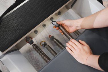 Pilates için elastik yayları seçiyorum. Spor salonundaki pilates teçhizatının ayarlanması, güç, esneklik ve vücut kontrolü konularına odaklanma, pilates seansına hazırlık.