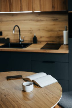 Siyah dolabı olan şık bir ev mutfağı, ahşap bir aksan duvarı ve rahat bir çatı katı yemek odası. Konfor, yemek ve okumak, kitap, bardak ve akıllı telefon için mükemmel. Hiç kimse, metin boşluğu 