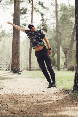 Yetişkinler bir ormanın içinden atlar, neşe ve özgürlük hissini ifade eder. İnsanoğlu doğadaki enerjik anın tadını çıkarıyor. Arka planda ağaçlar ve doğal, topraksı bir manzara var..