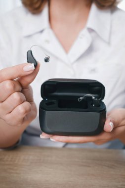 Hastanın işitme cihazını dahili güç bankası olan özel taşınabilir Smart Charger ile şarj etmesi. Erkeklerin elindeki dava işitme cihazlarını kuru ve güvenli tutuyor.