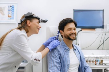 Adamın klinikte randevusu var. Doktor işitme rehabilitasyon kliniğinde danışmanlık yapıyor. Orta yaşlı adam için dijital cihaz seçecek. Doktor danışman hasta.