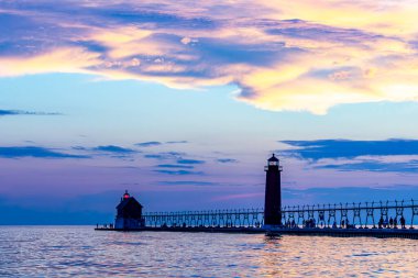 Grand Haven, Michigan 'da gün batımı, deniz feneri gökyüzünü pastel maviler, morlar ve sarılarla dolduruyor. Yüksek kalite fotoğraf