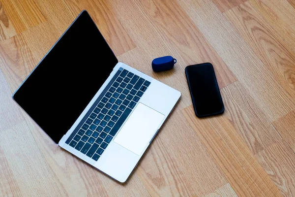 Bilgisayar, akıllı telefon ve kulaklıklar ahşap masada.
