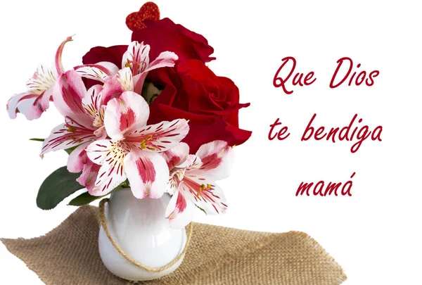 close-up of small white vase with red roses and pink flowers on a white background with the Spanish phrase \