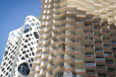 Milenyum Binghatti binasının yüksek çözünürlüklü yakın çekimi Cheddar Peynir Kulesi, O-14 binası arka planda, Business Bay, Dubai 'de. Keskin kenarlı balkonlar ve mavi gökyüzü arkaplanı