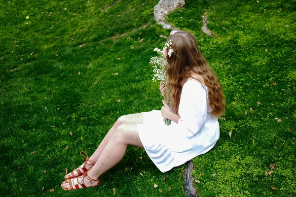 Uma Menina Vestido Branco Sentado Grama Com Buquê Suas Mãos — Fotografia de Stock