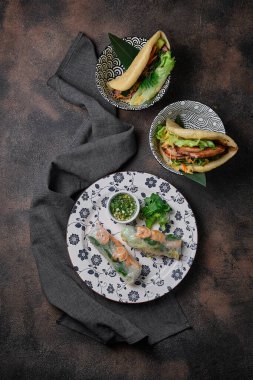 Spring Roll ve iki çeşit Gua Bao tabakta koyu arkaplanda. Üst görünüm
