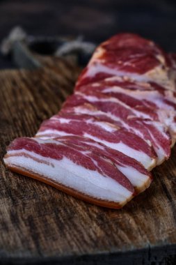 Tahtaya tütsülenmiş domuz pastırması ve birkaç kesik parça.