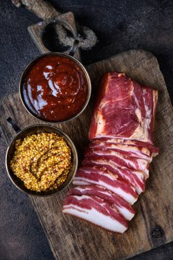 Tahtaya tütsülenmiş domuz pastırması ve birkaç kesik parça.