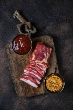 Tahtaya tütsülenmiş domuz pastırması ve birkaç kesik parça.