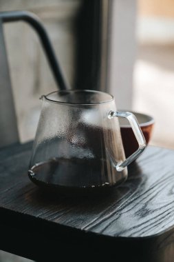 Tahta masada, cam çaydanlıkta sade kahve.