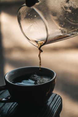 Cam çaydanlıktan bir fincana koyu kahve dökülüyor.