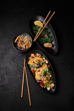 Chuka wakame, Cesare salad and Miso soup and chopsticks in japanese stile on a black concrete background. Top view