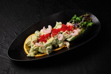 Avocado salad with shrimp on a black concrete background. Top view