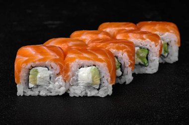 salmon sushi roll on black concrete background