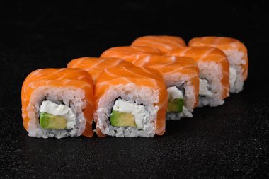 salmon sushi roll on black concrete background