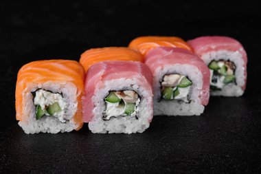 Salmon and Tuna sushi roll with Eel inside on black concrete background