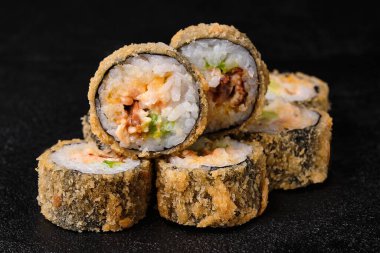 baked sushi rolls with ell on black concrete background. Deep-fried sushi roll. Close-up. 