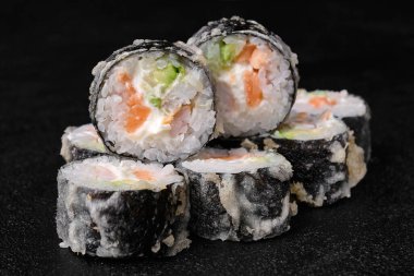 baked sushi rolls with salmon on black concrete background. Deep-fried sushi roll. Close-up. 