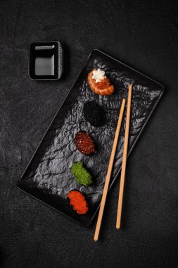 Set of Gunkan Maki Sushi with different types of fish and caviar on black background. Sushi menu. Japanese food sushi set gunkans.