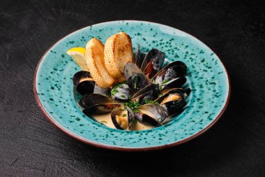 Oysters in cream sauce on blue plate on black concrete background