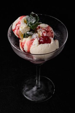 Ice-cream witnmint and red fruit sauce on black concrete background