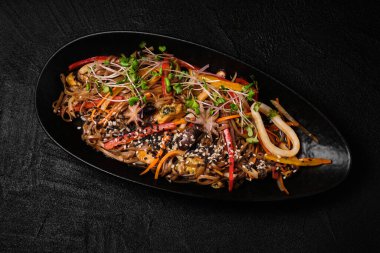 Stir-fried yakisoba noodle with seafood on black concrete background.  Asian food style. Top view