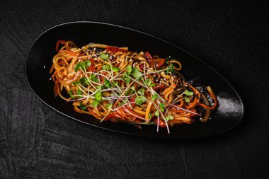 Stir-fried yakisoba noodle with vegetable on black concrete background. Asian food style. Top view