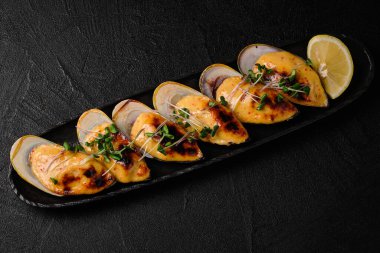 Baked mussels with cheese on black concrete background