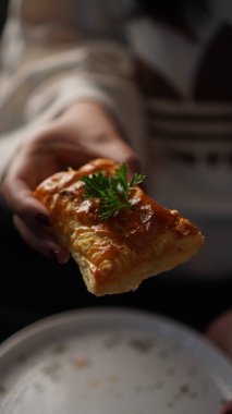 Ev yapımı kek tutan bir el ya da elmalı ve karamelli puf böreği, üstünde maydanozlu garnitür olan