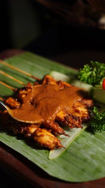 Fıstık soslu Sate Ayam (Tavuk satay). Endonezya 'nın popüler sokak yemeklerinden biri. Tahta masada muz yaprağı tabağında servis ediliyor. Seçici odak.